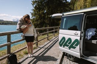 Gay Travel Index: Ein lesbisches Paar umarmt sich neben einem Off Camper am Ufer des Walchensees in Deutschland