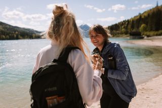 Zwei junge Frauen lachen sich beim Wandern am Walchensee an