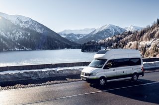 VW Grand California on mountain road in winter alpine panorama 