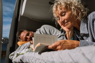 Frau liest im Bett des Campers